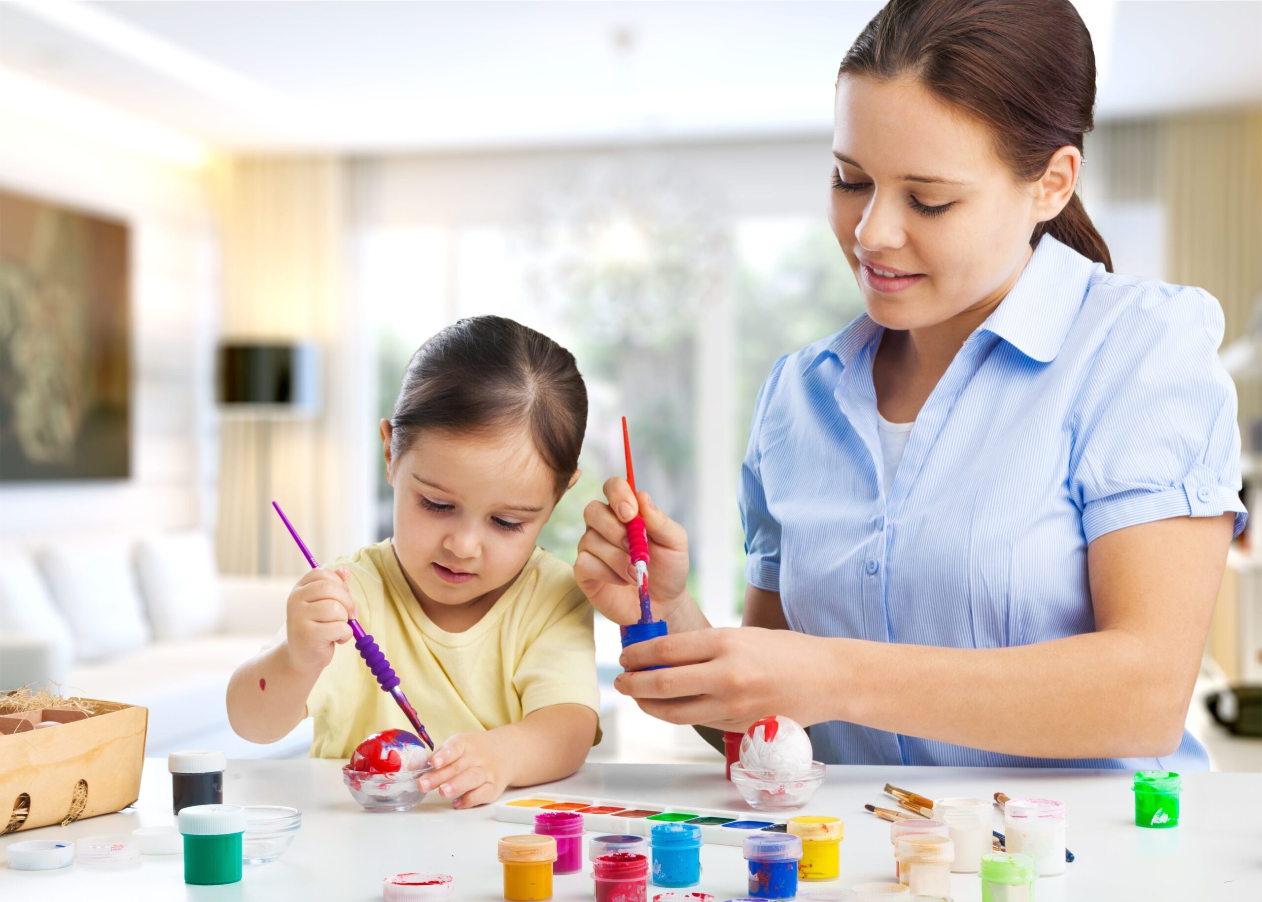 Mother and her daughter painting eggs